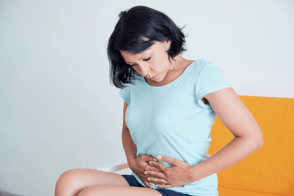 Sitting woman holding stomach pain gastroenterology