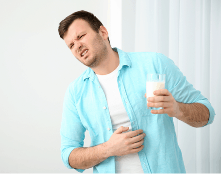 man holding milk and stomach unpleasant expression